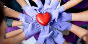 Groep handen van mensen met handschoenen aan dragen een hart