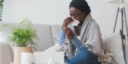 Donkere vrouw heeft last van verkoudheid en de griep en ze controleert haar temperatuur