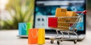 Pakketten in een winkelwagen met wat boodschappentassen met op de achtergrond een laptop en een webshop voor online winkelen