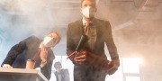 Zakenman met een masker houdt een brandblusser vast in een kantoor waar brand en rook is