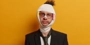 Brildragende zakenman in pak met verband om zijn hoofd in verband met verwondingen